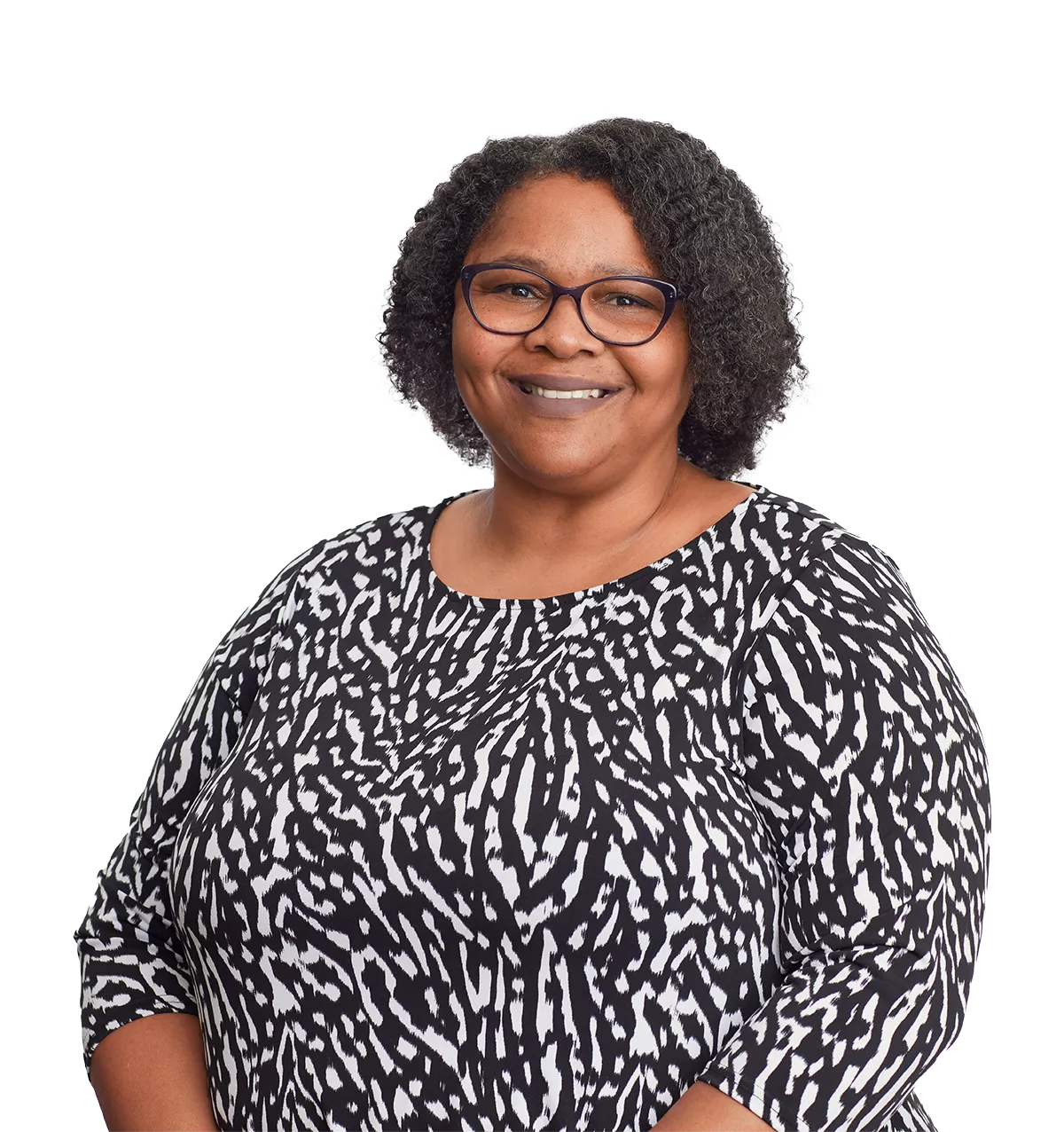 woman with curly hair, glasses, and a patterned black and white top smiles against a white background.