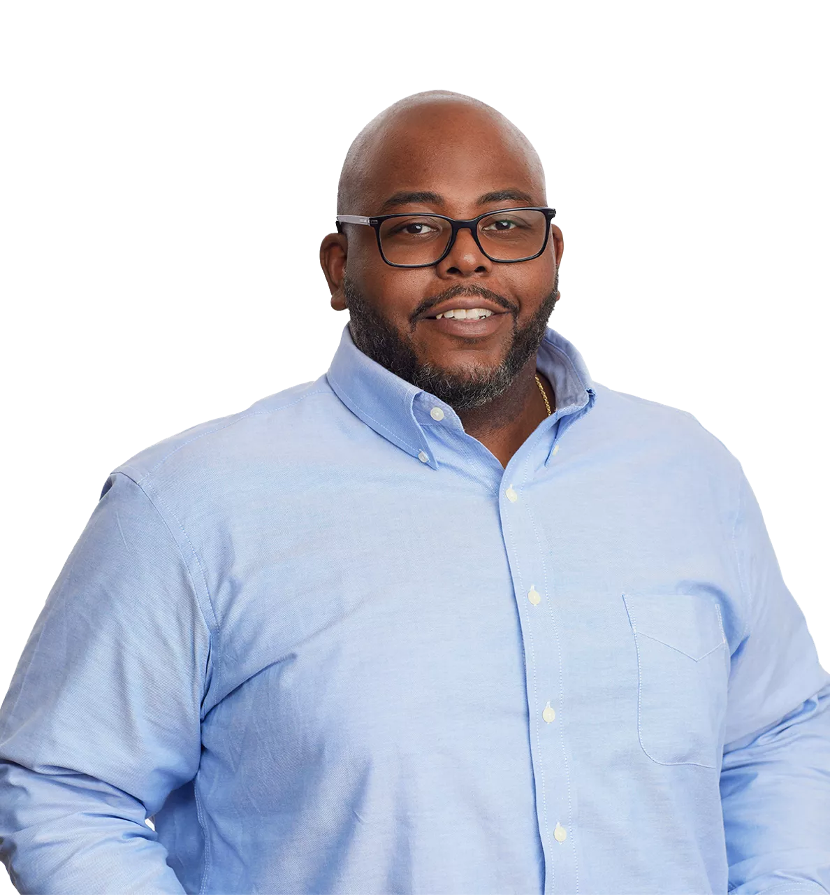 smiling man in glasses and a light blue button-up shirt stands against a plain white background.