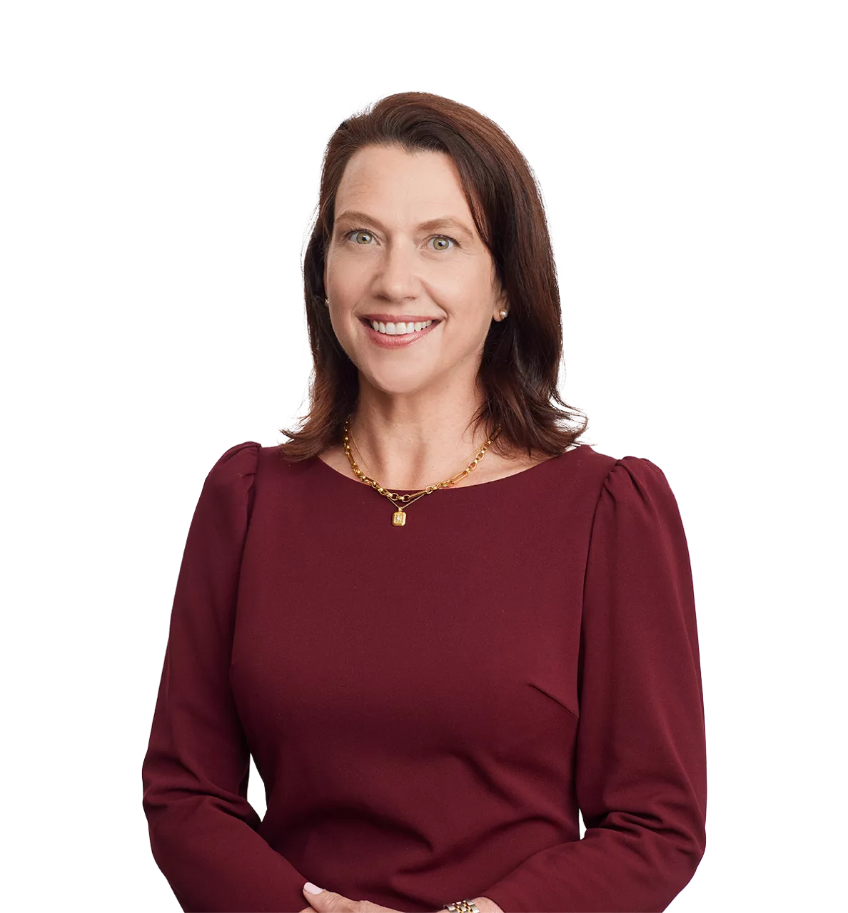 woman with brown hair in a maroon dress, smiling, hands clasped, wearing a gold necklace, white background.