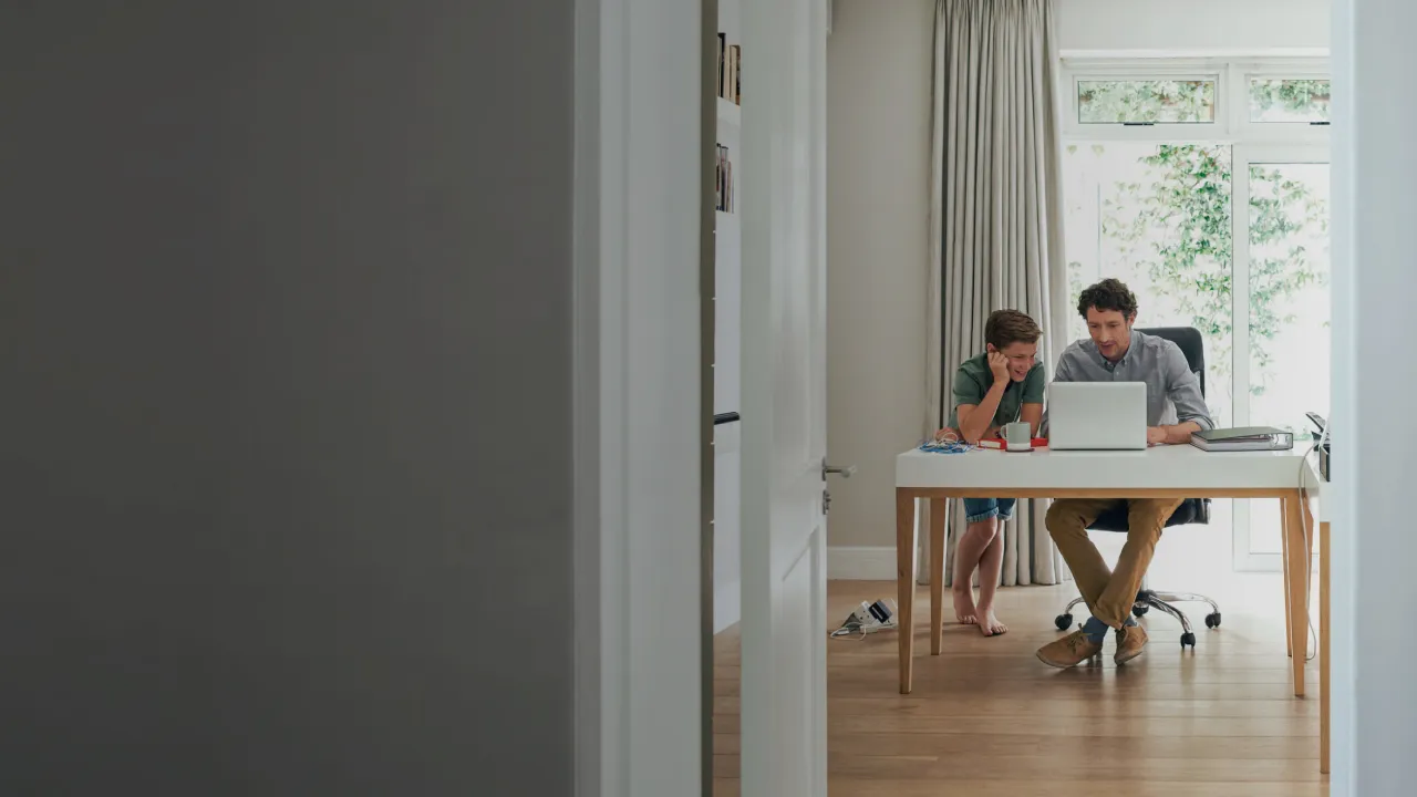 father-and-son-sitting-at-desk-looking-at-laptop-together