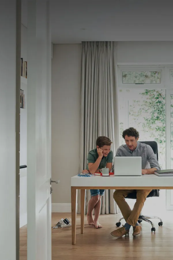 father-and-son-sitting-at-desk-looking-at-laptop-together