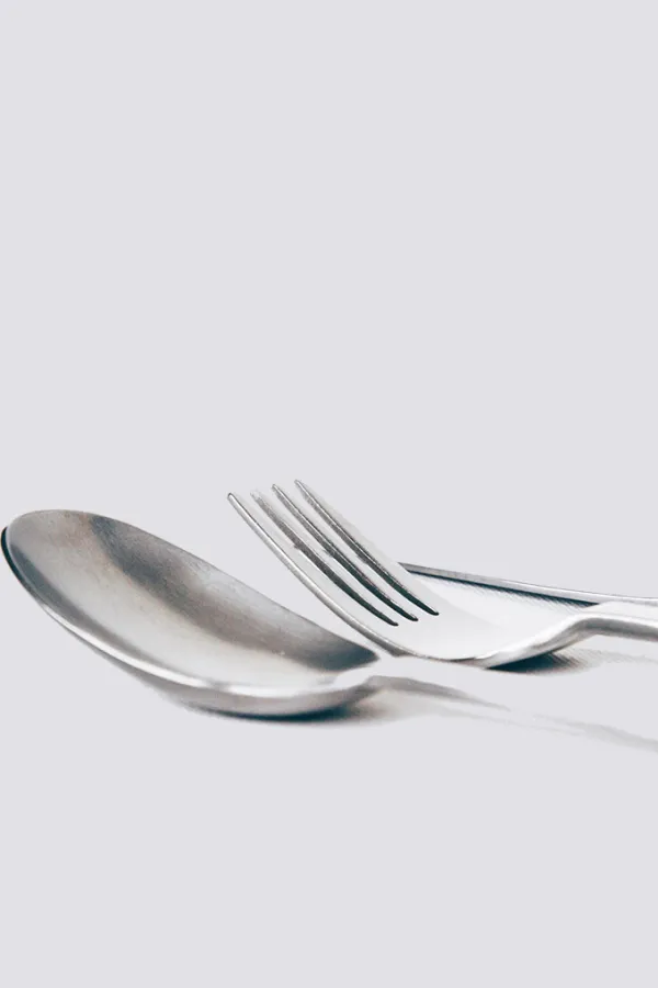 close up of metal spoon, fork, and knife on white surface