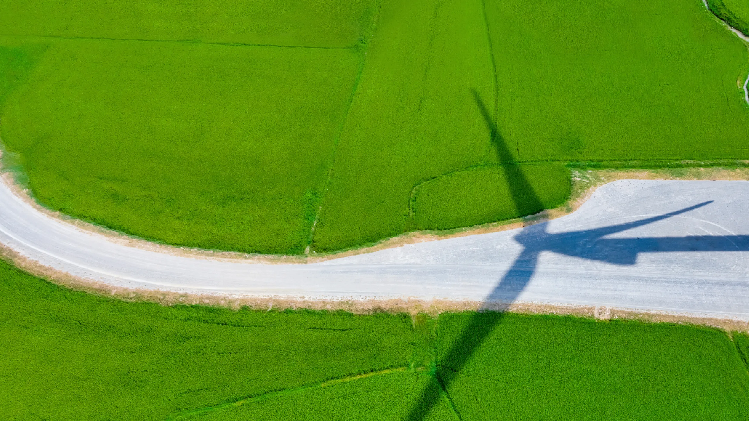 windmill-shadow-on-green-field-and-gravel-road