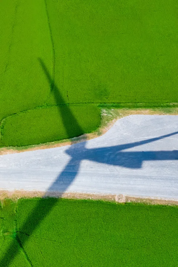windmill-shadow-on-green-field-and-gravel-road