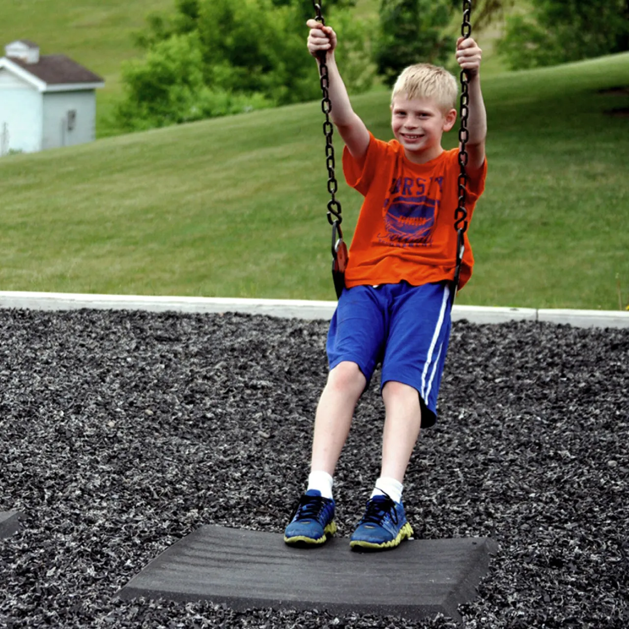 child-smiling-on-swing-in-rubber-filled-playground-small