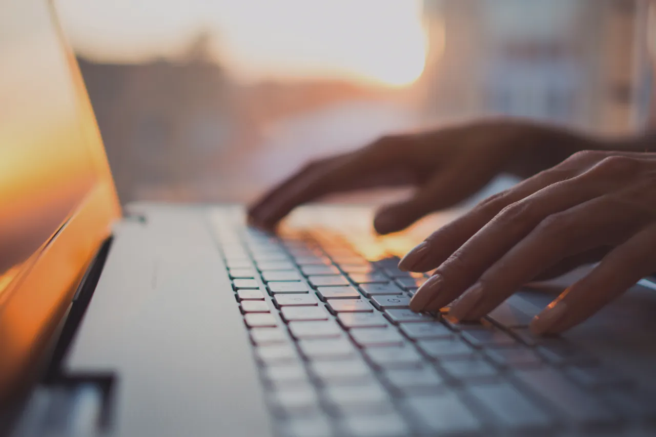 close-up-of-laptop-keyboard-with-hands-paused-over-keys