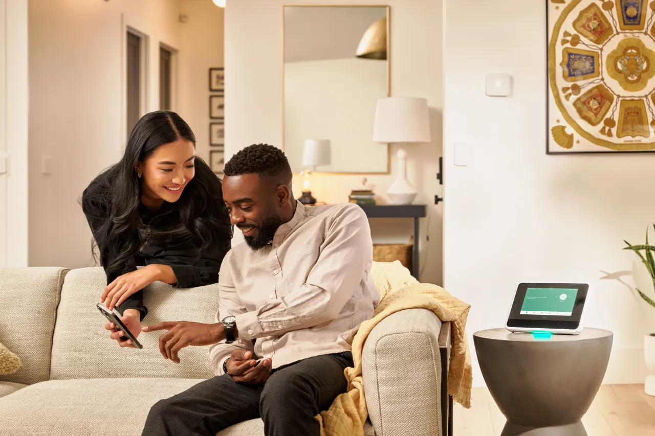 couple viewing phone in living area next to Vivint smart hub.