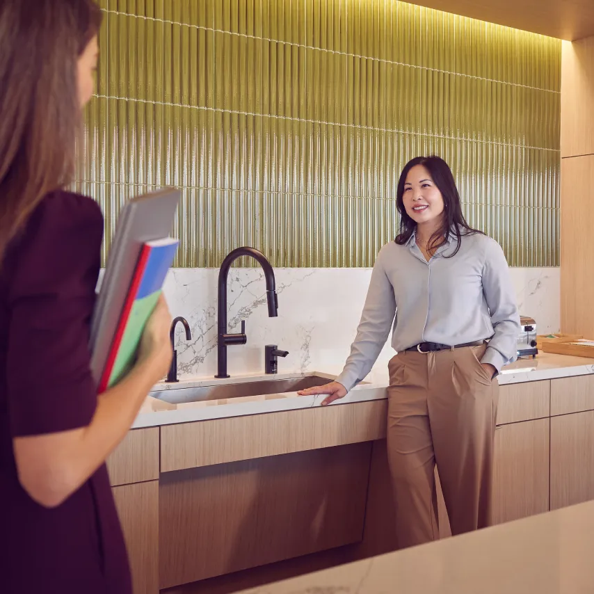 female coworkers meet in a brightly colored break room.