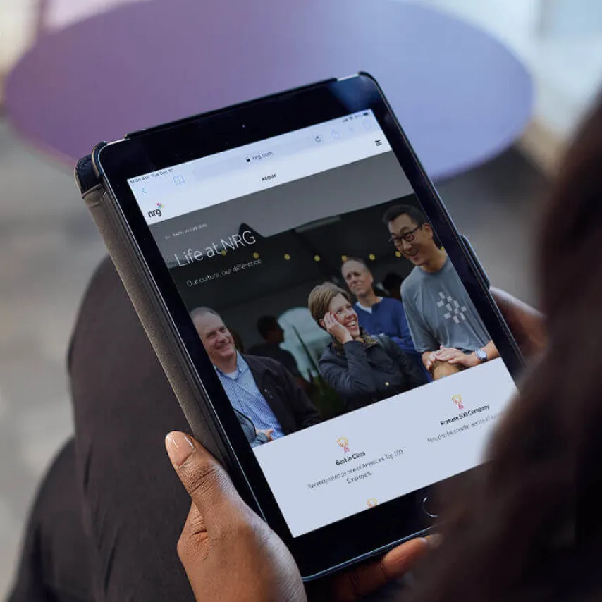 tablet screen in persons hands with life at NRG page showing.
