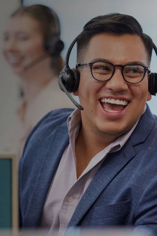 male-employee-with-headset-lauging-along-with-coworkers-at-desk
