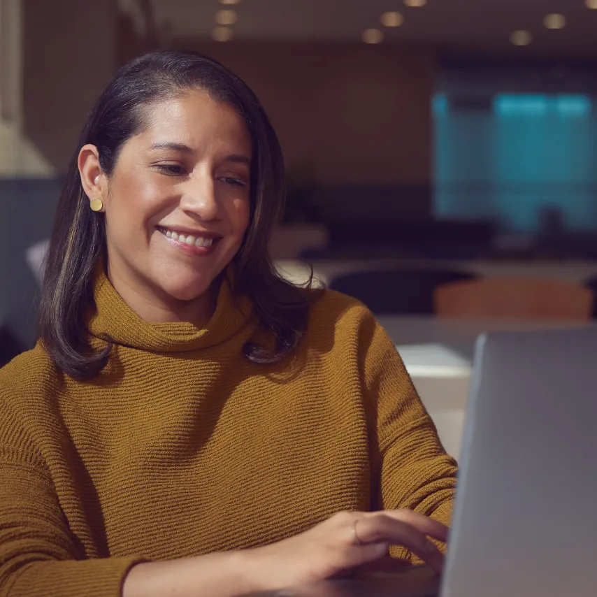 smiling woman types on a laptop.