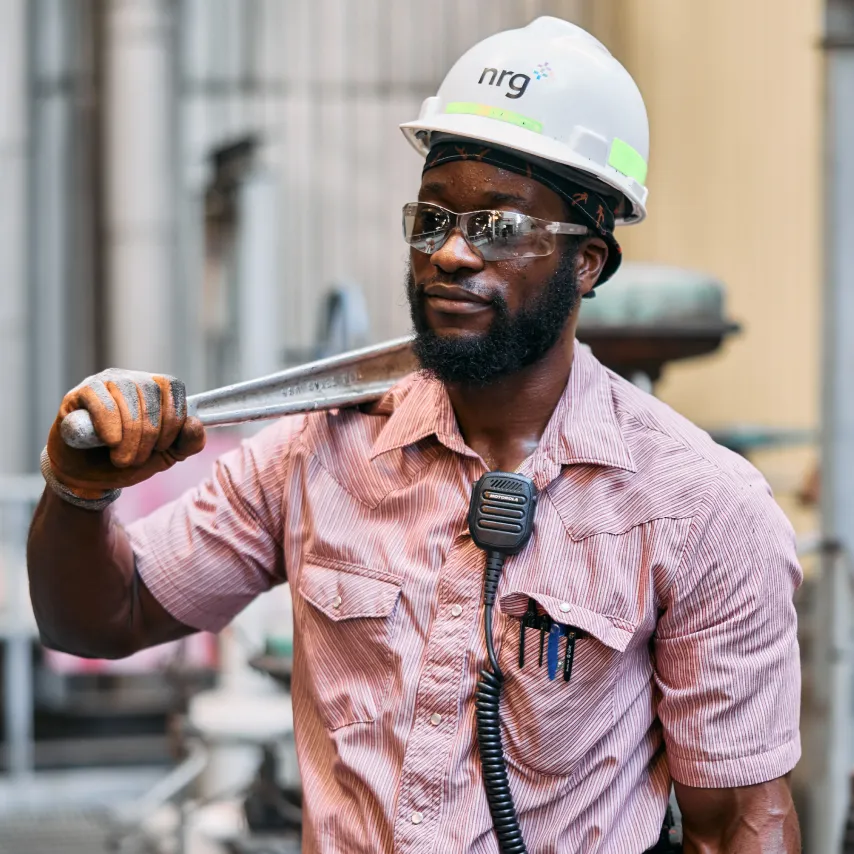 strong power plant worker holds a large wrench over his shoulder.