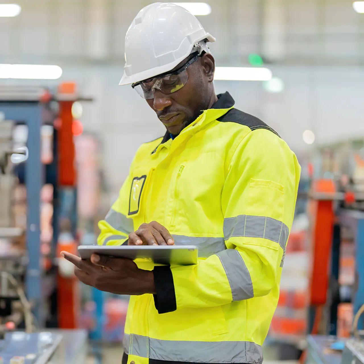 male factory worker in hard hat looking at tablet