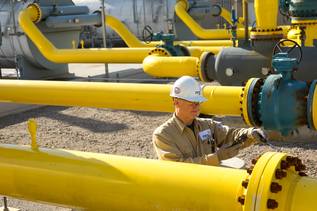 plant worker inspecting natural gas pipeline with equipment.