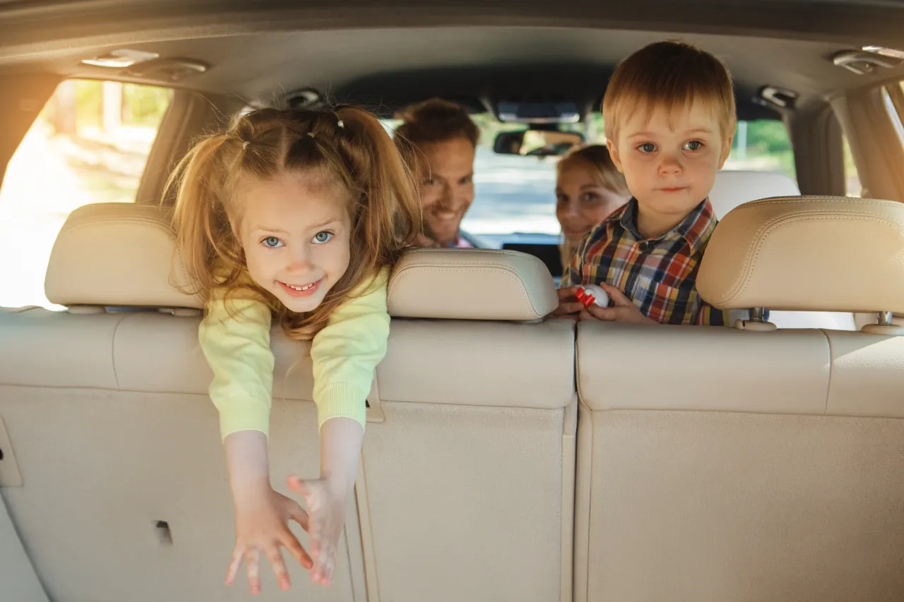 family in van looking and smiling out the back door.