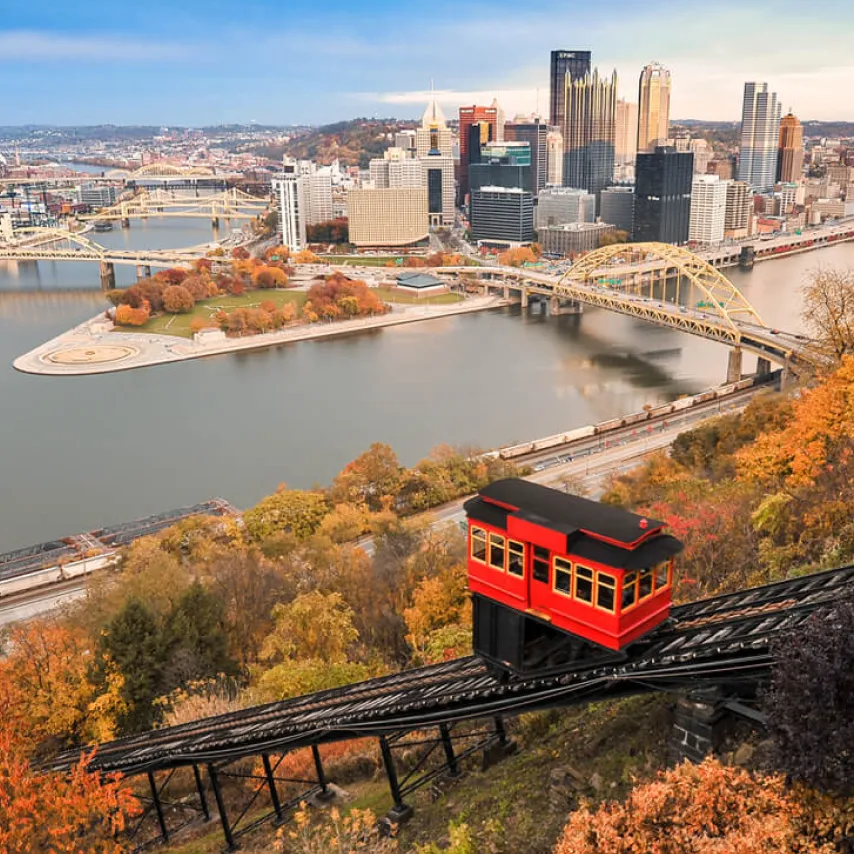 Pittsburgh funicular with downtown city skyline and bridges.