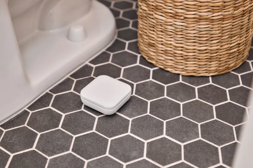 Vivint water sensor on tiled bathroom floor.