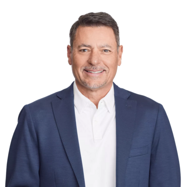smiling man in a blue blazer and white shirt standing against a plain white background.