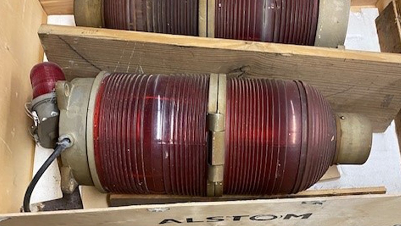 two large red industrial signal lights in a wooden crate with ALSTOM partially visible on the side.