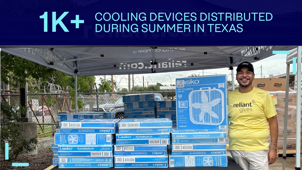 smiling man stands by stacked fans under a tent; sign reads 1K+ Cooling Devices Distributed During Summer in Texas.