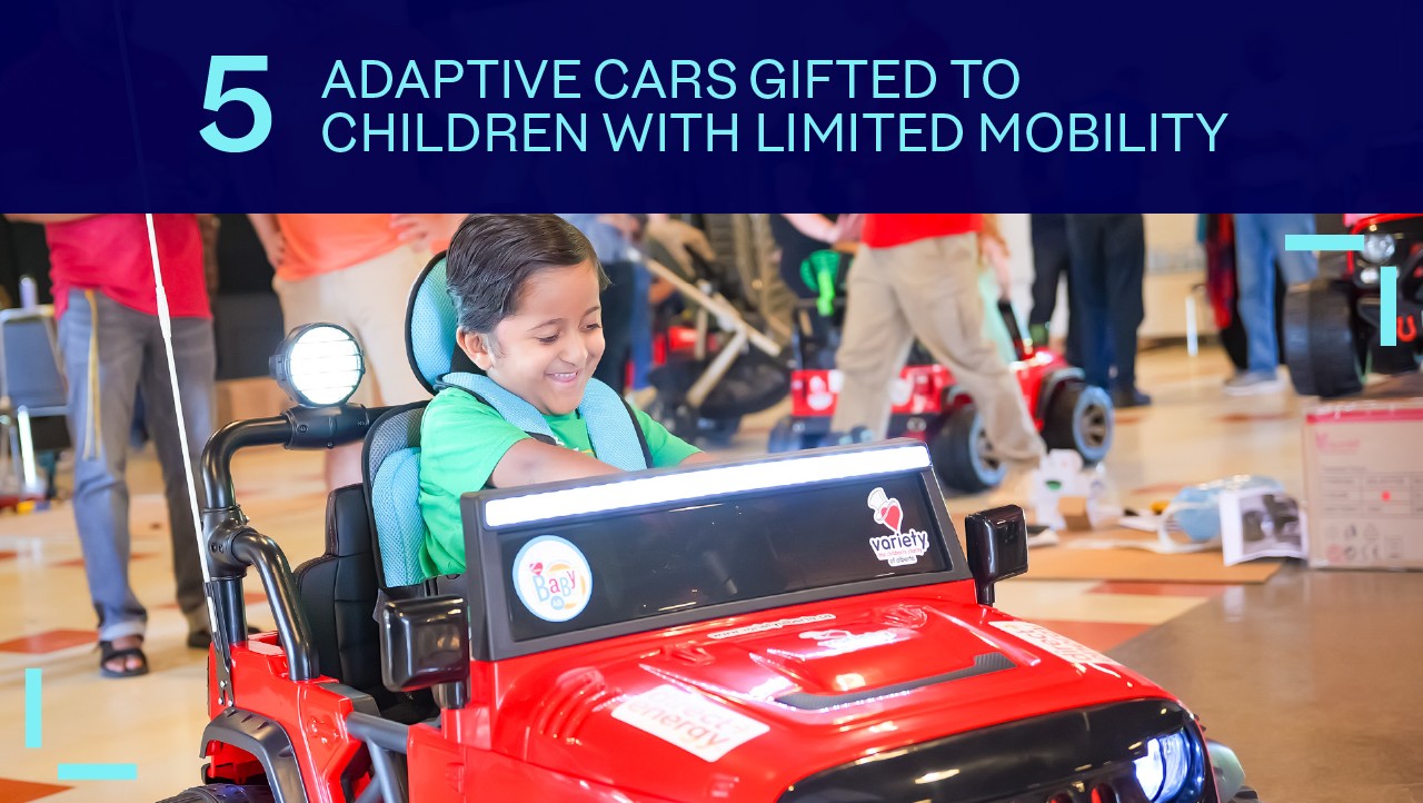 smiling child drives a red adaptive toy car indoors; headline above reads, 5 adaptive cars gifted to children.