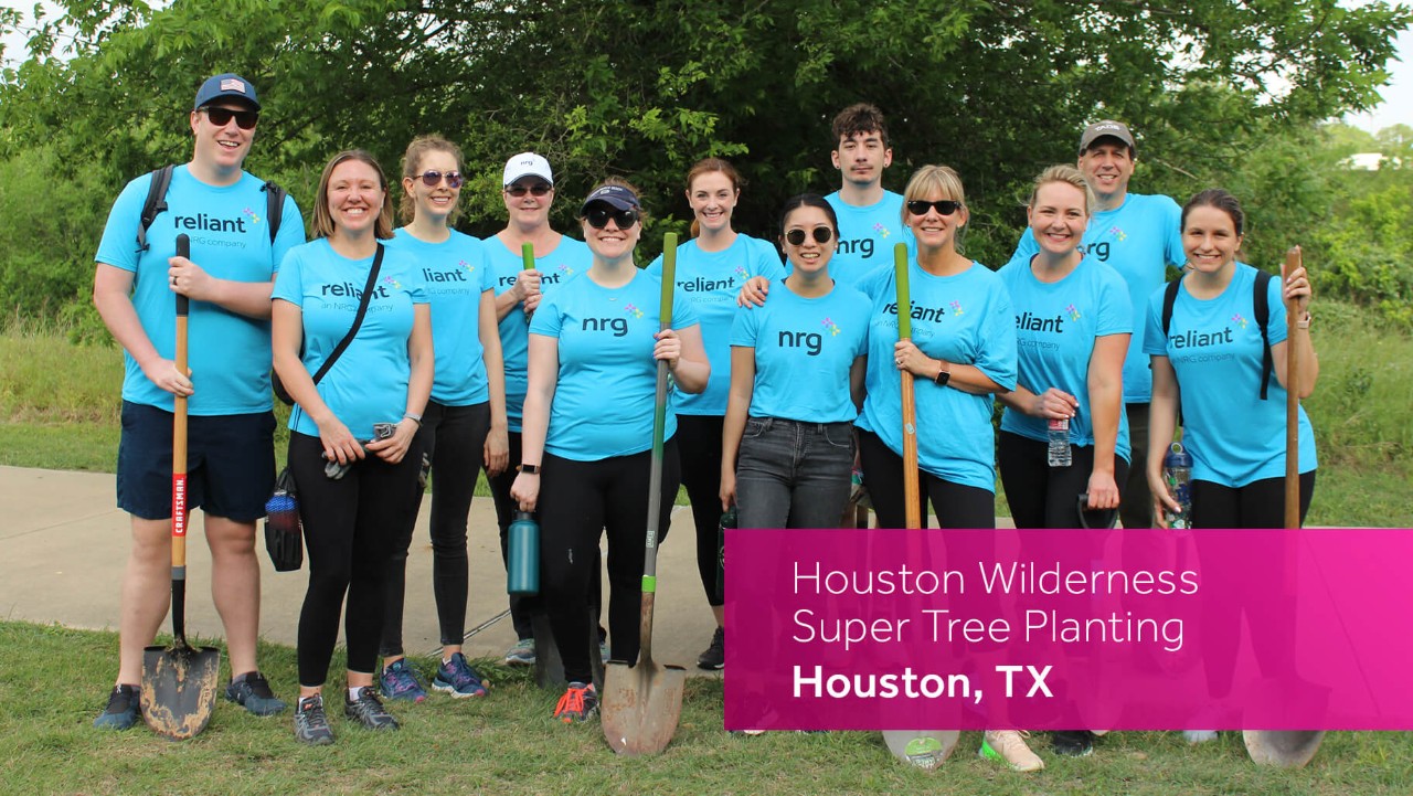 twelve people in blue shirts pose outdoors with shovels for a tree planting event in Houston, TX.